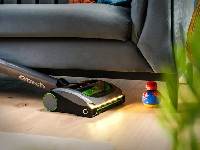 Gtech  AirRAM 2 vacuum cleaner cleaning under a sofa with a toy visible on the floor.