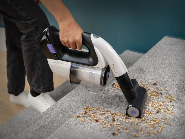 Multi Platinum handheld vacuum  being used to pick up dirt and debris on carpeted stairs.