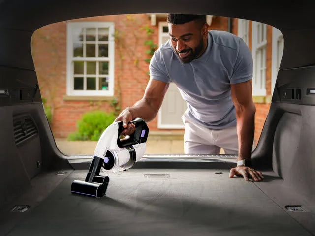Man using Multi Platinum cordless handheld vacuum cleaner in the trunk of a car.