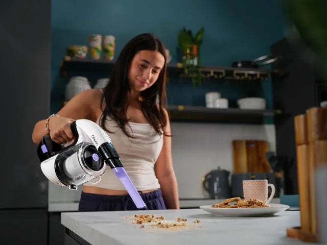 Lady using MultI Platinum handheld cordless vacuum with crevice tool fitted to pick up crumbs on kitchen counter,