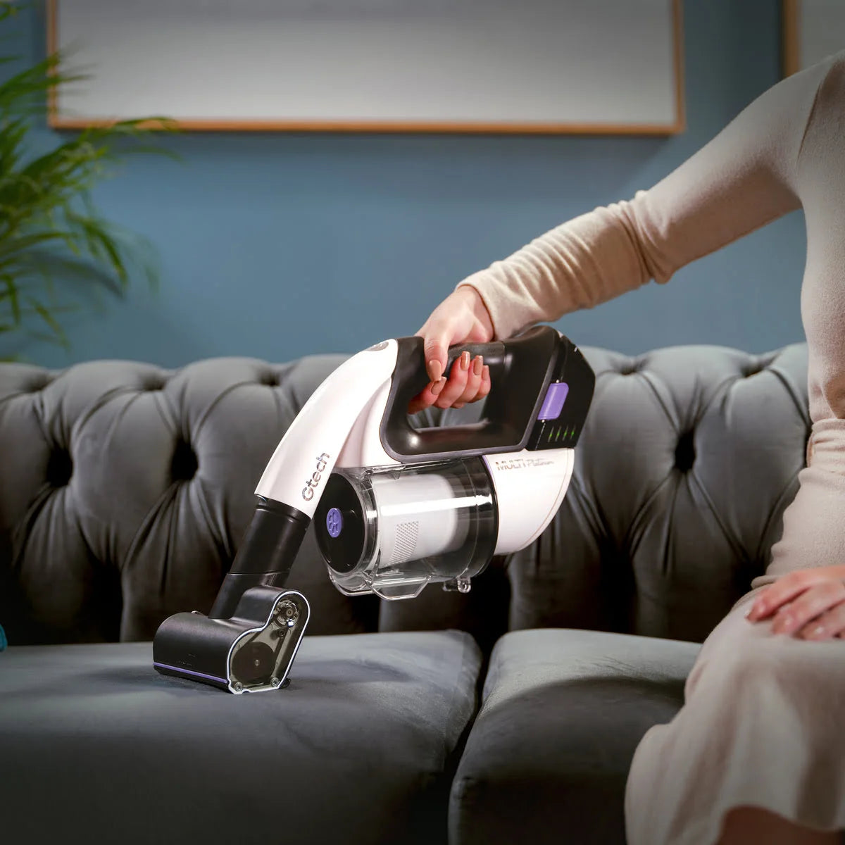 Multi Platinum cordless handheld vacuum cleaner with power head attachment being used by lady on sofa,