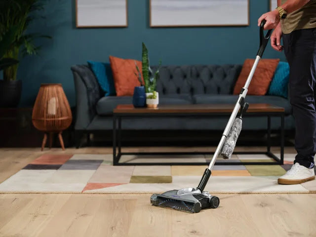 Person using a SW02 cordless carpet sweeper in a living room.