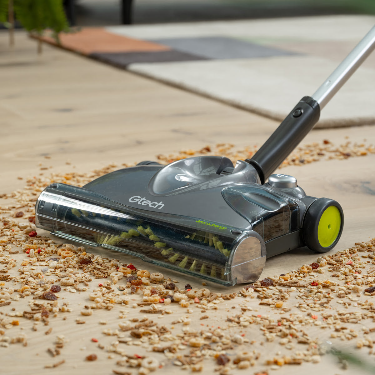 Close up of SW22 cordless carpet sweeper picking up cereal on wooden floor.