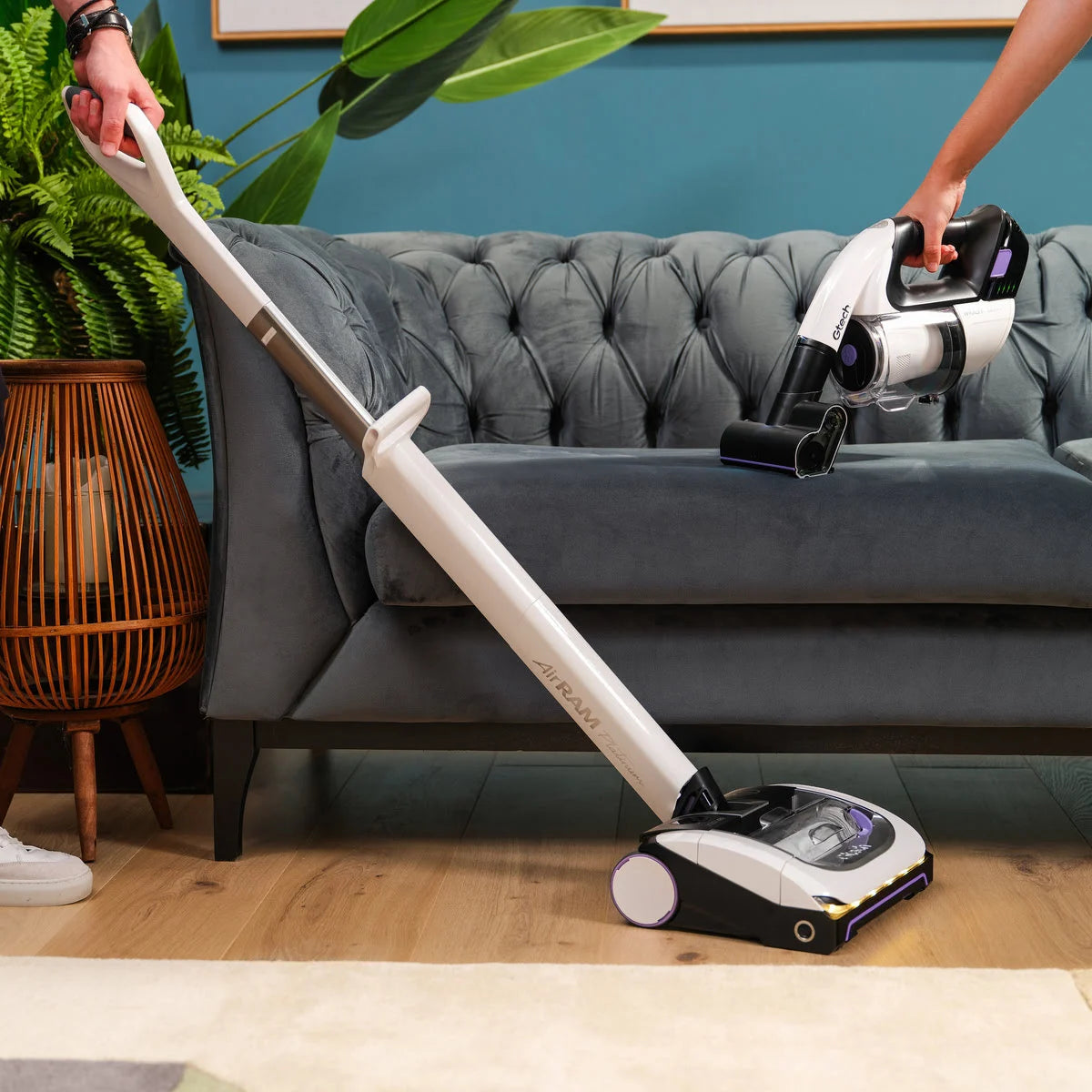 Close up of System Platinum bundle with AirRAM Platinum Anti Hair Wrap cordless vacuum on wooden floor and Multi Platinum cordless handheld vacuum on sofa.