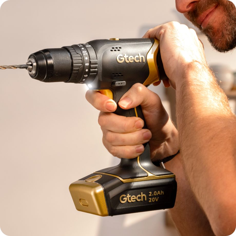 Person using a Gtech cordless drill with a plain background