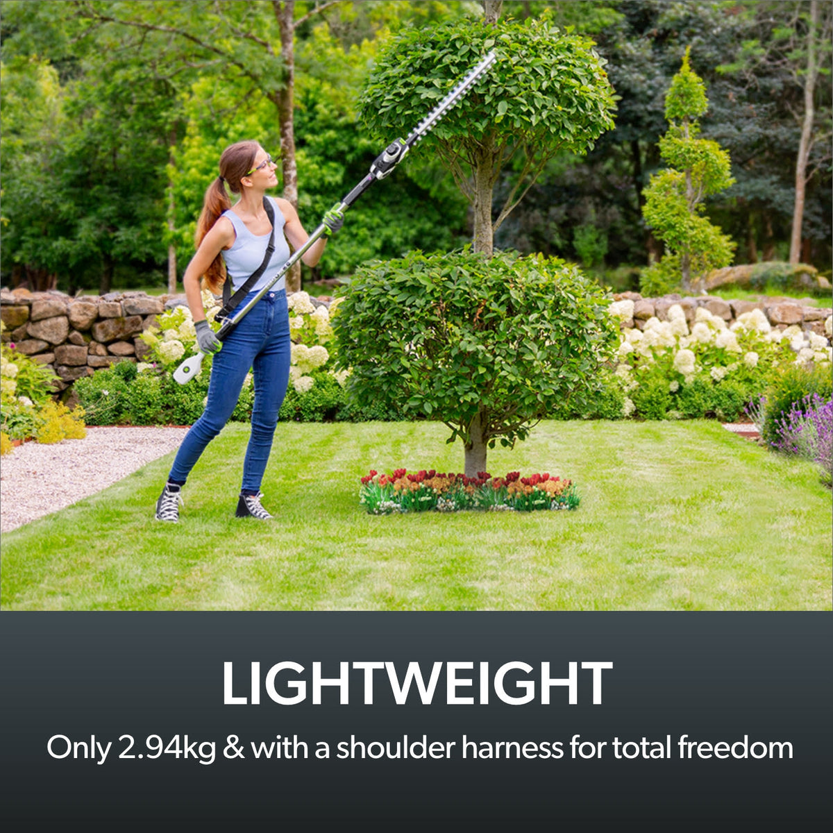 Woman Person using Gtech HT50 rechargeable hedge cutter on tall yard hedge